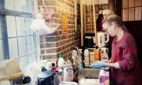 Kvinde med handsker på gør rent i køkken