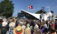 Foto af hovedscenen under åbningstalen på Folkemødet 2018 med blå himmel og Dannebrog vejende over sig.