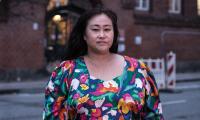 Kvinde med egen erfaring fra psykiatrien står foran Huset for Psykisk Sundhed i København iført farvet kjole og løst hår